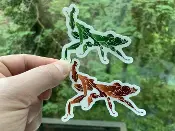 A person holding up a Sticker Ghost Mantis with two frogs on it.